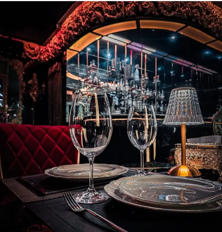 Table with crystal glasses and a lamp in front of the bar